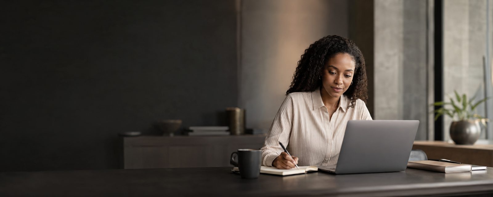 A learner taking notes at her laptop